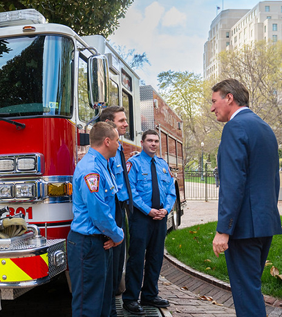 ba lính cứu hỏa và Thống đốc đứng trước một chiếc xe cứu hỏa
